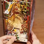 Festive miniature Christmas village book nook with warm LED lights and detailed buildings