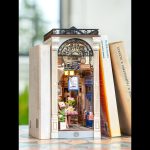 handmade-book-nook-featuring-retro-arcade-scene Handmade book nook featuring retro arcade scene with metal railings, ceramic tiles, and brass accents between hardcover books