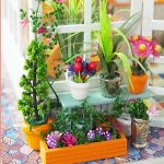 handmade-miniature-house-with-floral-decorations Handmade miniature house with floral decorations on wooden shelf