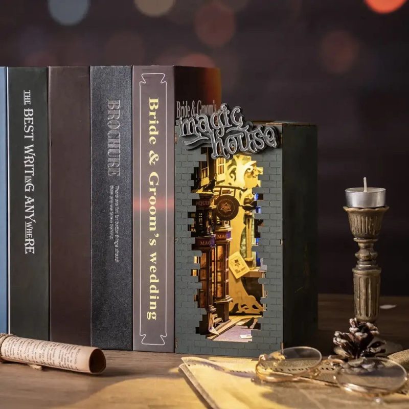 illuminated-book-nook-miniature-house-scene Illuminated fantasy book nook with warm amber LED glowing softly on a wooden bookshelf